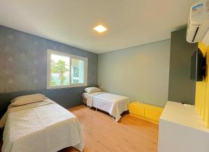 ein Krankenzimmer mit zwei Betten und einem Fenster in der Unterkunft Espaçoso apto no Centro de Gramado in Gramado