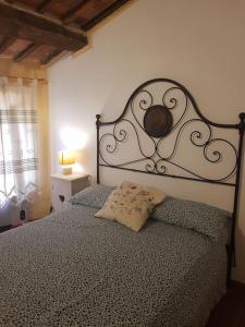 um quarto com uma cama com uma cabeceira de metal em Casa Della Rosa em Pitigliano