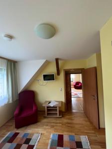 a living room with a red chair and a table at Privatzimmer Familie Pair/Schmoll in Spital am Semmering