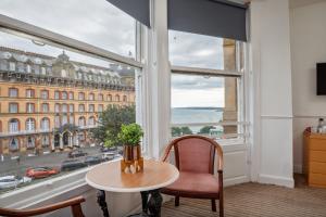 una camera con tavolo e sedia e una grande finestra di Serenity Guest House a Scarborough