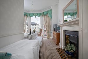a bedroom with a bed and a fireplace and a window at Serenity Guest House in Scarborough