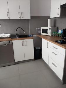 a kitchen with white cabinets and a sink and a microwave at Domek Pod Prehybą -Agroturystyka in Gaboń