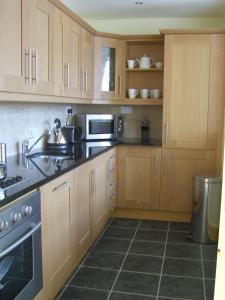 uma cozinha com armários de madeira e electrodomésticos de aço inoxidável em Castle Quay em Ballinadee