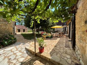 a patio with a tree and a table and an umbrella at Demeure du Vallon - Chambres d'Hôtes de Charme in Azerat