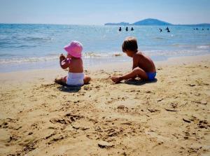 duas crianças brincando na areia na praia em Residenza Gli Oleandri em Formia