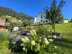 un jardín con flores blancas y una casa blanca en 2-Zimmer Ferienwohnung an ruhiger Lage, en Triesenberg