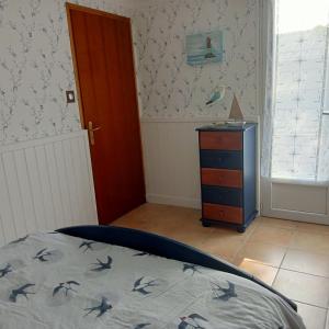 a bedroom with a bed and a dresser and a door at Maison La Belvérine in Beauvoir-sur-Mer