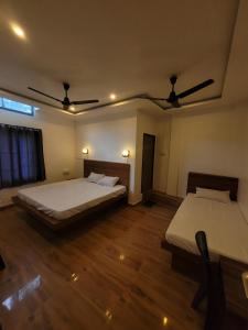 two beds in a room with wooden floors at Dream Lodging in Silchar