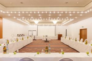a conference room with white tables and a screen at Wyndham Garden Donaueschingen in Donaueschingen