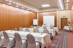 a conference room with white tables and chairs and a whiteboard at Wyndham Garden Donaueschingen in Donaueschingen