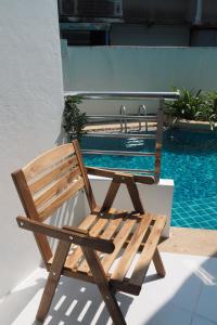 a wooden chair sitting next to a swimming pool at The Beach Bangsaen by Thanthita next to Wonnapa beach FREE DISNEY PLUS in Bangsaen