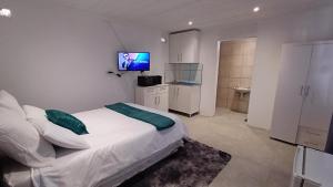 Schlafzimmer mit einem Bett und einem TV an der Wand in der Unterkunft Ozizi Lodge in East London