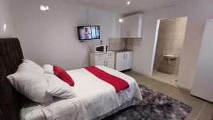 Schlafzimmer mit einem Bett und einem TV an der Wand in der Unterkunft Ozizi Lodge in East London