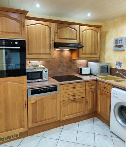 a kitchen with wooden cabinets and a stove top oven at GÎTE DE LA FONTAINE in Wangen