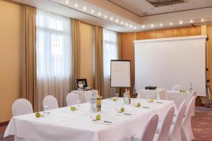 a conference room with white tables and chairs and a screen at Wyndham Garden Donaueschingen in Donaueschingen