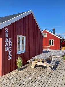 a red building with a picnic table on a deck at Fishermans cabin in Lofoten, Stamsund in Stamsund