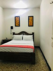梅爾加的住宿－HOTEL MACEO MELGAR，卧室配有一张墙上有两张照片的床。