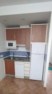 uma cozinha com um frigorífico branco e um micro-ondas em Islantilla primera linea de playa, piscina, parking na Islantilla