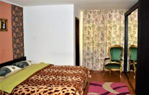 a bedroom with a bed and a green chair at Pensiunea Sorina Deea in Bicazu Ardelean