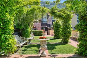 um jardim com uma fonte e bancos e árvores em BV Grand Hotel Assisi em Assis