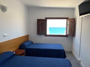 a room with two beds and a window with the ocean at Hotel Playa in Mojácar