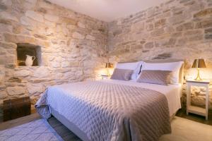 - une chambre avec un grand lit dans un mur en pierre dans l'établissement Villa Bella Vista Heritage Oasis, à Podstrana