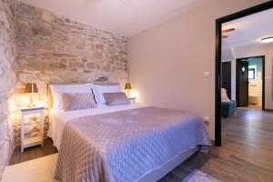 a bedroom with a large bed and a stone wall at Villa Bella Vista Heritage Oasis in Podstrana +77 photos
