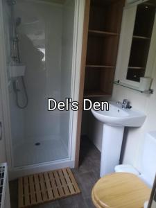 uma casa de banho com um chuveiro, um lavatório e um WC. em Del's den lakeside weeley bridge em Weeley