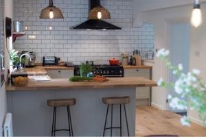 a kitchen with a counter with two bar stools at Beaston Cottage in Totnes