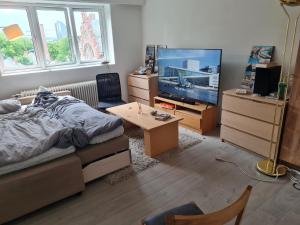 a bedroom with a bed and a tv and a table at Private room in to roomsapartment (Grunneløkka) in Oslo