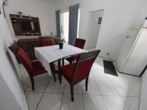 a dining room with a white table and red chairs at Apto Ruan Pelinca in Campos dos Goytacazes
