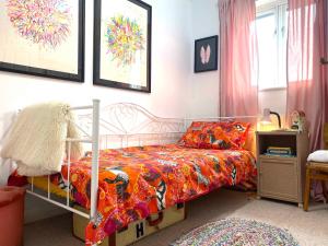 um quarto com uma cama com um edredão colorido em Artist's eclectic Town House close to river em Woodbridge