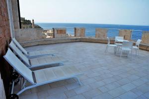 a patio with chairs and tables and the ocean at Castello Tafuri in Portopalo