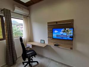 Habitación con escritorio, silla y TV. en FOUR IN ONE RESIDENTIAL HOMES, en Limbe