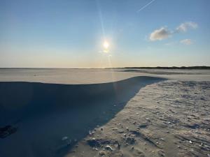 uma praia com o sol refletindo na água em Logeren bij de bakker em Schiermonnikoog