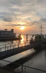 a boat is docked at a dock with the sunset at Logeren bij de bakker in Schiermonnikoog