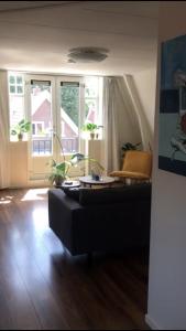 een woonkamer met een zwarte bank en een raam bij Logeren bij de bakker in Schiermonnikoog