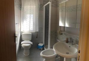 a white bathroom with a toilet and a sink at Villa Dacla in Lampedusa