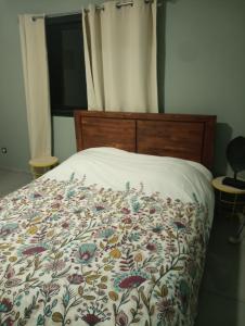 a bed with a flowered comforter on it at Couleur pastel in Saint-Louis