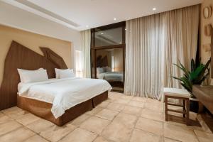 een slaapkamer met een groot bed en een groot raam bij The Cliff Resort in Riyad