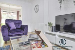 un salon avec une chaise violette et une télévision dans l'établissement Purple Velvet - 2 Bed Home Spacious - Basildon Essex Upto 5 Guests, Free Wifi , Free Parking, à Basildon