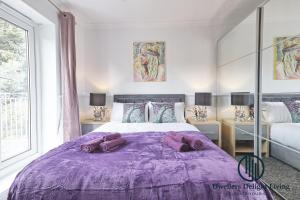 Purple Velvet - 2 Bed Home Spacious - Basildon Essex Upto 5 Guests, Free Wifi , Free Parking في باسيلدون: غرفة نوم مع سرير أرجواني ومخدات عليه