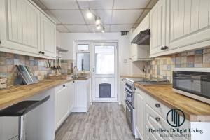 a large kitchen with white cabinets and a window at Purple Velvet - 2 Bed Home Spacious - Basildon Essex Upto 5 Guests, Free Wifi , Free Parking in Basildon