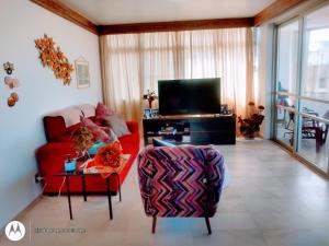 a living room with a red couch and a tv at Quarto em Apto Compartilhado BEIRA MAR in Maceió