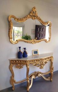 Una consola de oro con un espejo y jarrones. en Seaside SunFlower en Quinta do Lago