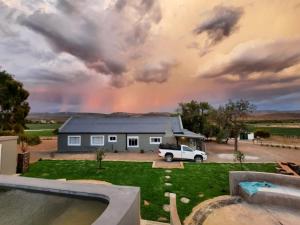 a rainbow in the sky over a house at Môreson Cottage in Klaarstroom +7 photos