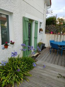 una casa con una puerta verde y una mesa en una cubierta en Maison d'hôtes les roses trémières, en Saclay