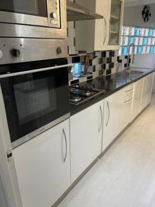 uma cozinha com armários brancos e um forno com placa de fogão em The Princes Dartford Stunning Entire Space em Kent