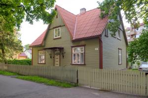 a green house with a red roof and a fence at Aiaviisa apartment in Pärnu