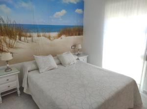 a bedroom with a bed and a painting of a beach at islantilla adosado piscina parking 1 minuto al mar in Islantilla